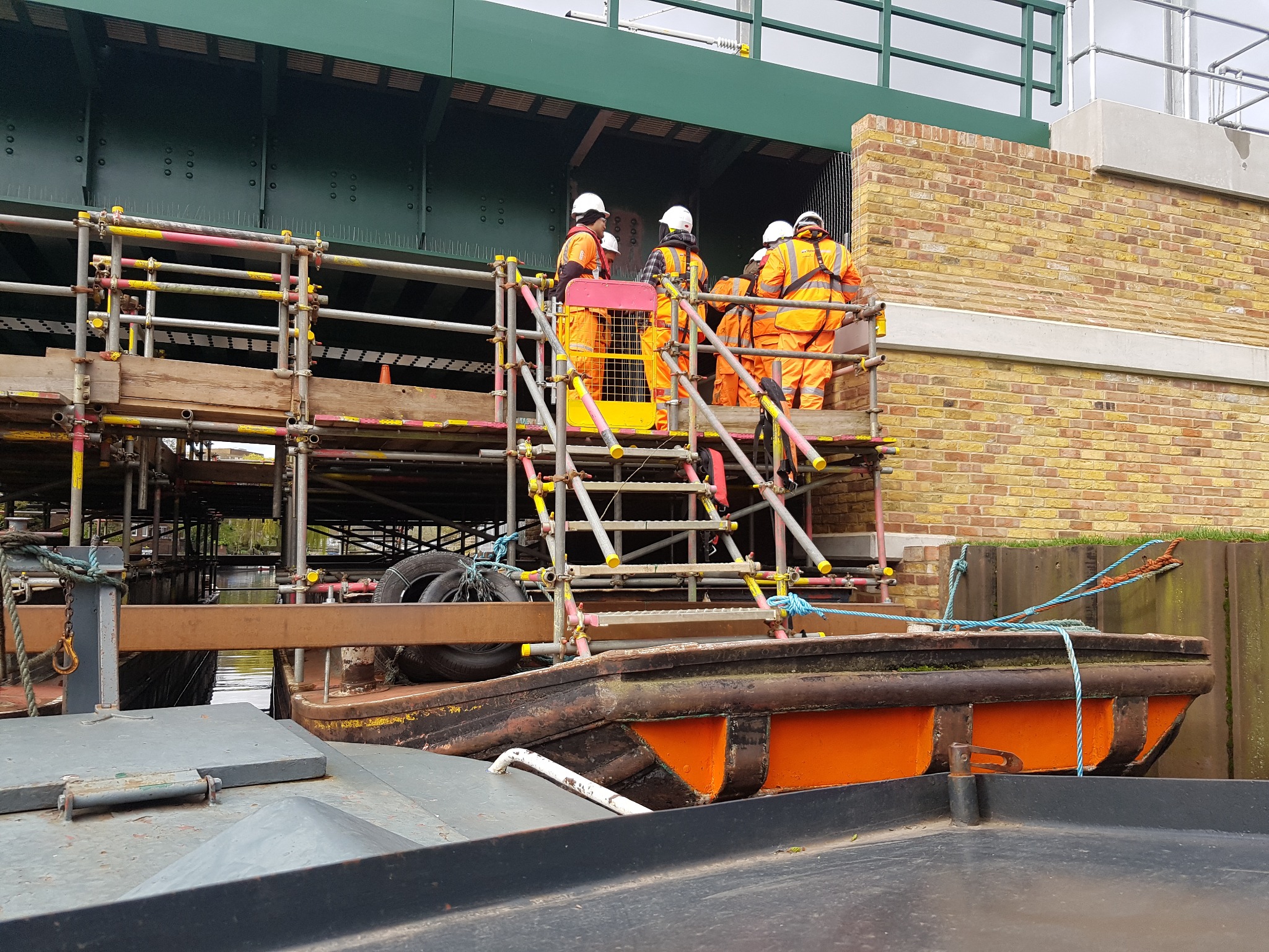 Multiple barges joined together beneath a railway bridge to form a working platform and crash deck