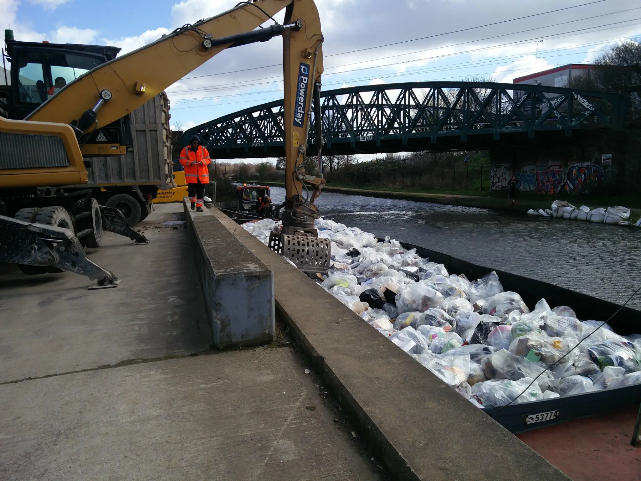 Powerday excavator unloading bagged dry mixed recycling from a WHH hopper at Old Oak Wharf