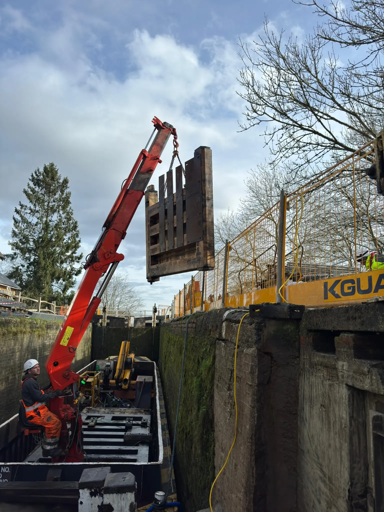 Red HIAB crane aboard Jumbo lifting a lock gate from the drained chamber