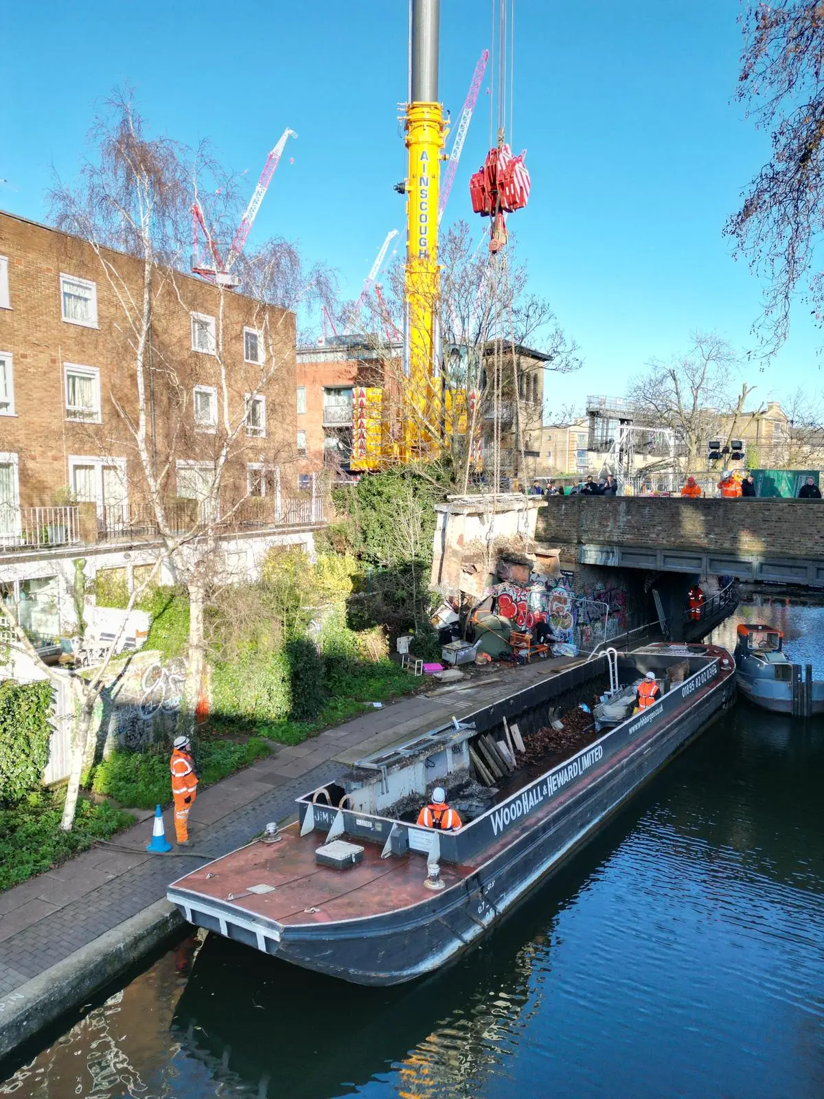WHH cargo barge and tug supporting a crane operation on an urban canal
